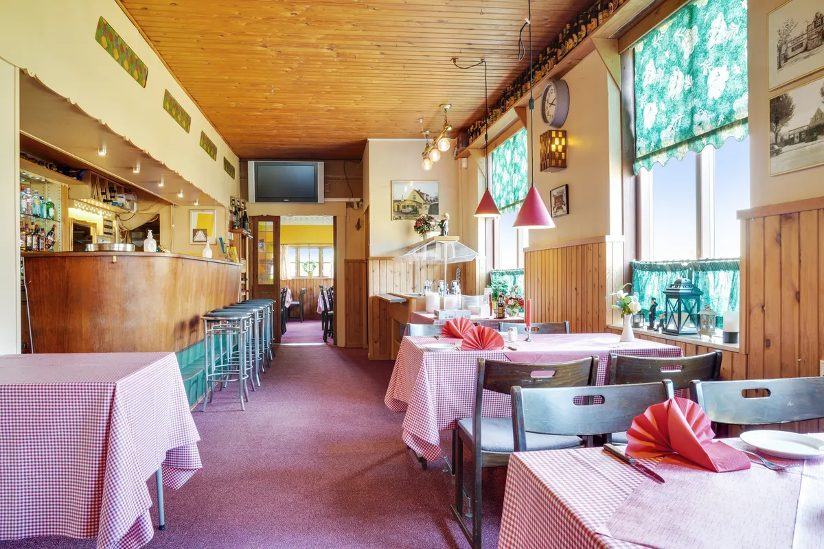 Et stort lokale med rødt og hvidt tæppe på bordene og stole og et gulv med møbler og lysekroner