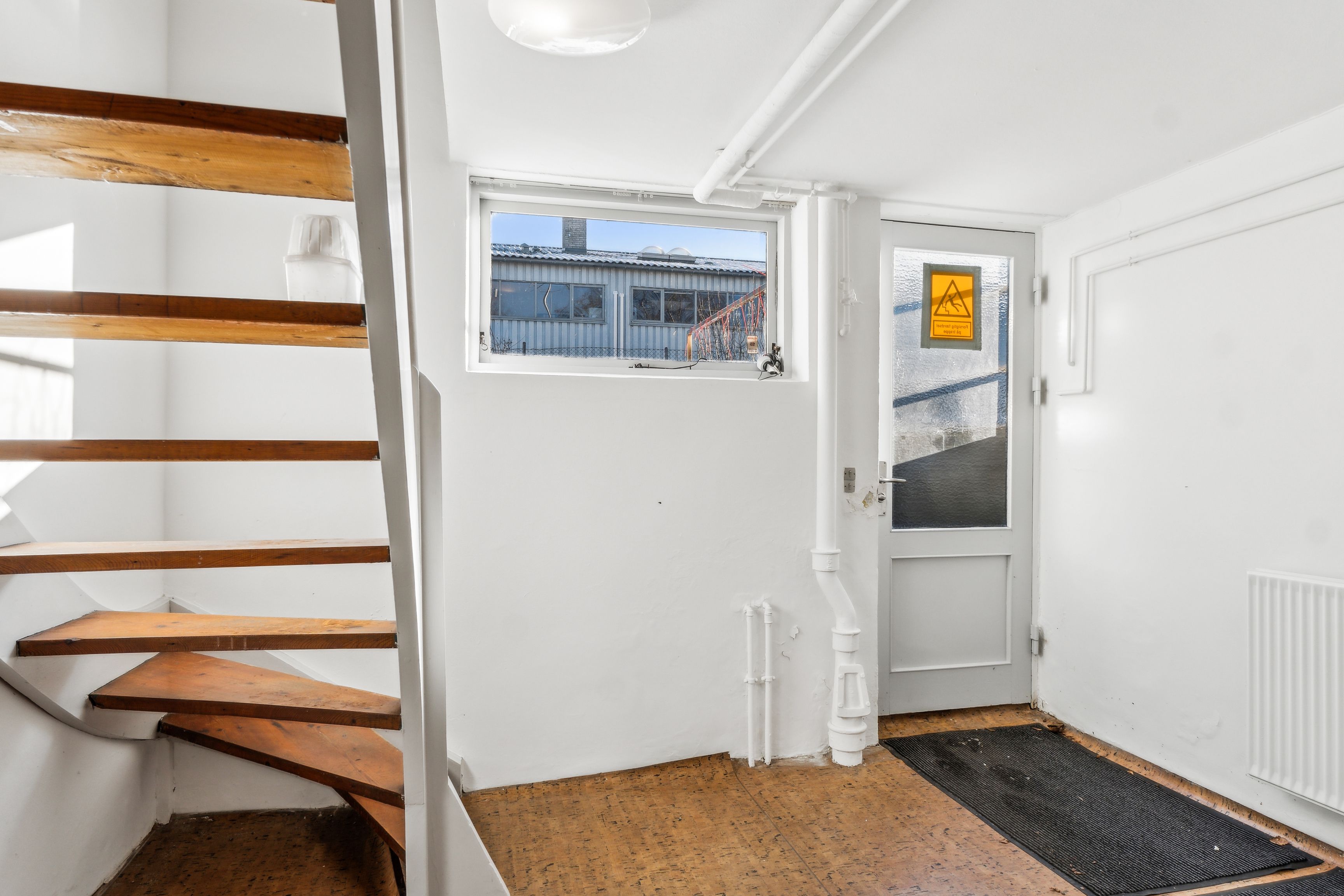 Foto af en indgangsdør med et skilt på, et badekar, en stigning, et vindue og et lys i loftet