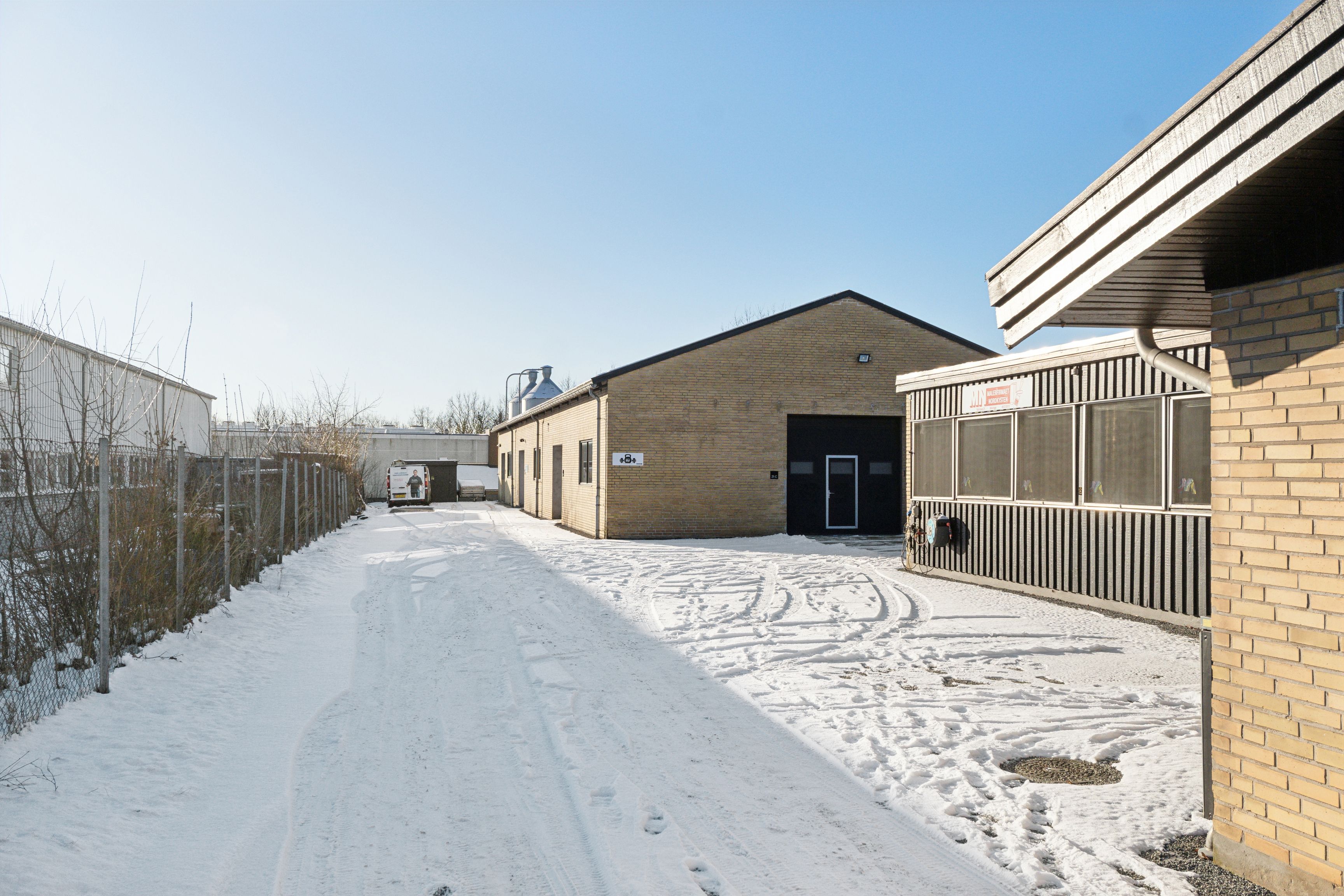 En vandret vej, der er snegedækket, og en bygning med højt tag og flere vinduer