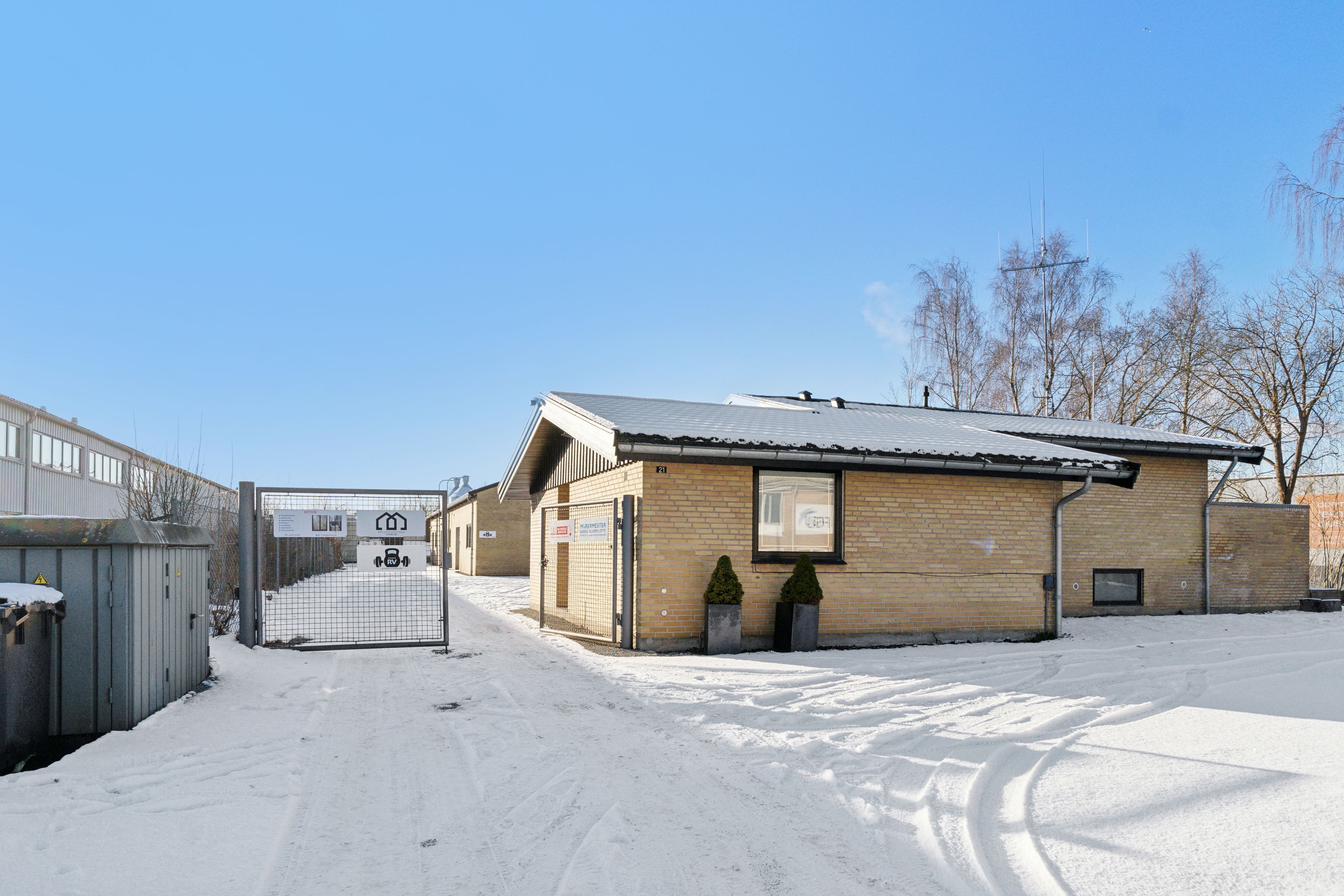 Et lille erhvervslokale i Helsingør med en åben port og to små planter i potter foran døren.