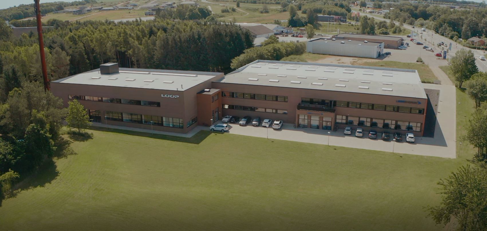 Kontorbygning med parkeringsplads og grønne områder på Gammel Sellingvej 1 i Østjylland. Flere biler parkeret udenfor.