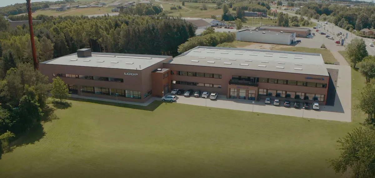 Kontorbygning med parkeringsplads og grønne områder på Gammel Sellingvej 1 i Østjylland. Flere biler parkeret udenfor.