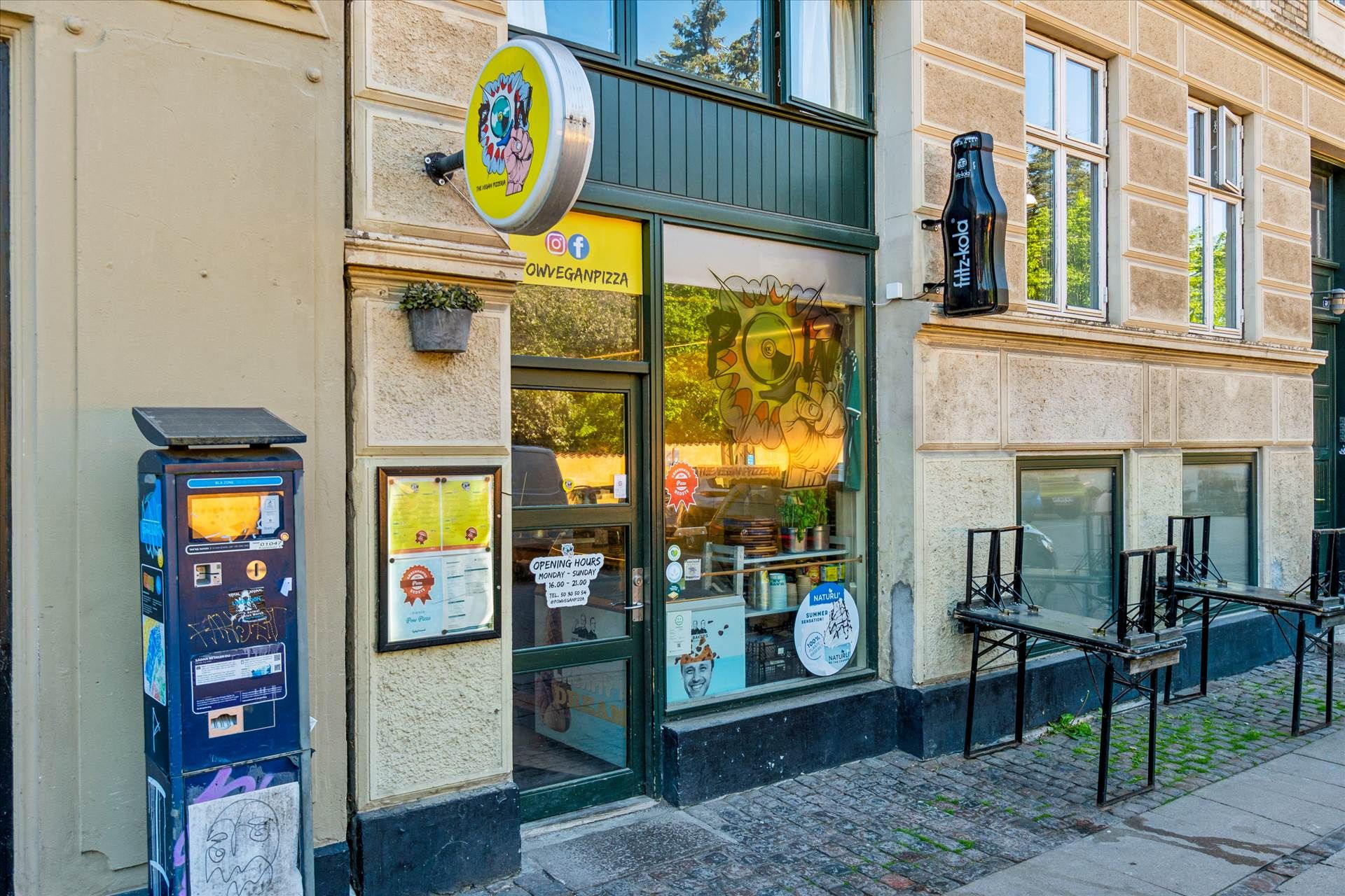 Et vegansk pizzeria ligger på Nørrebro, med en plante i potte og åbne vinduer med udsigt til en solrig gårdhave og et glasvæg