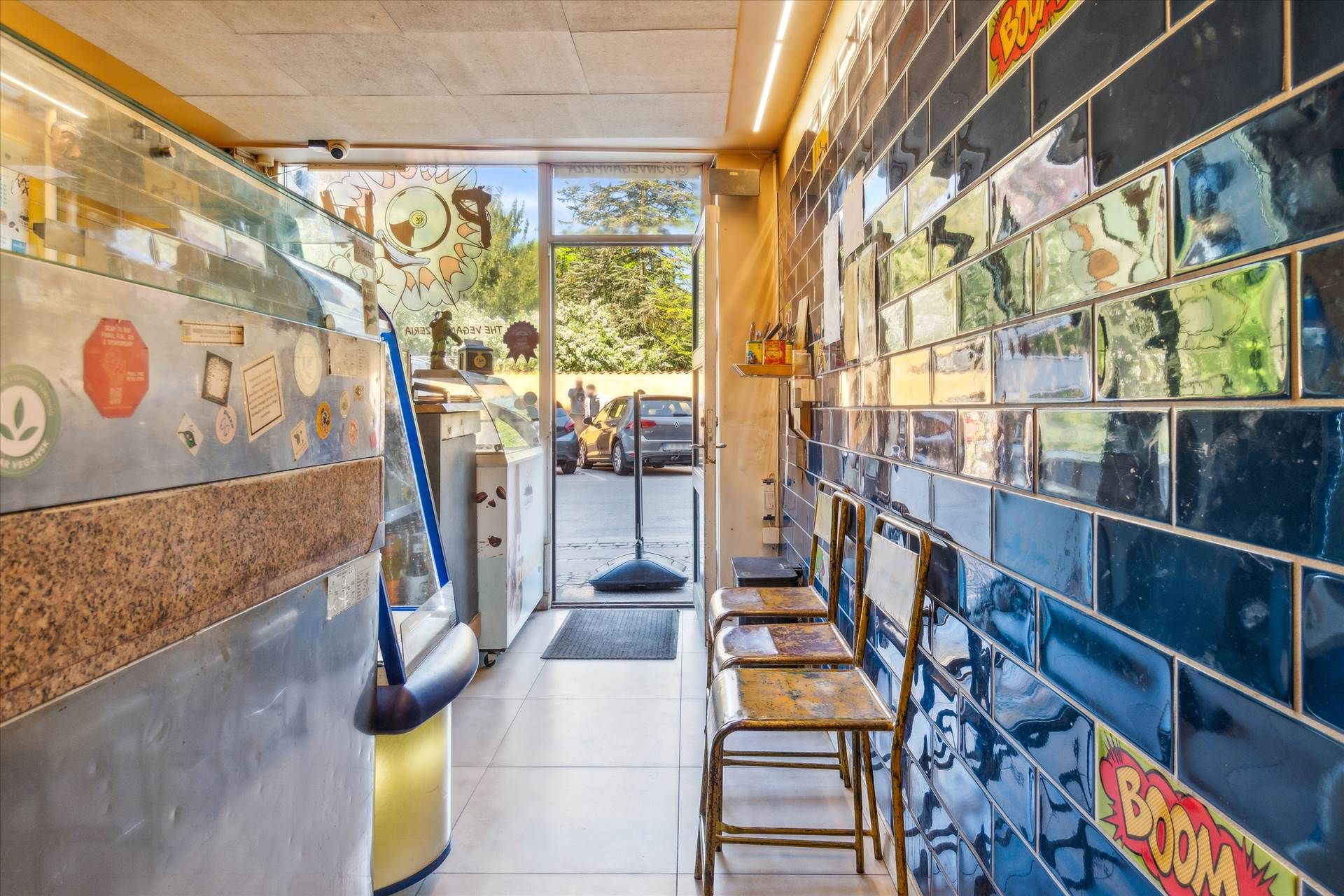 Butikslokale med gulvbelægning og højt loft, udstyret med moderne møbler og kunstværker. Lejemålet er centralt beliggende og