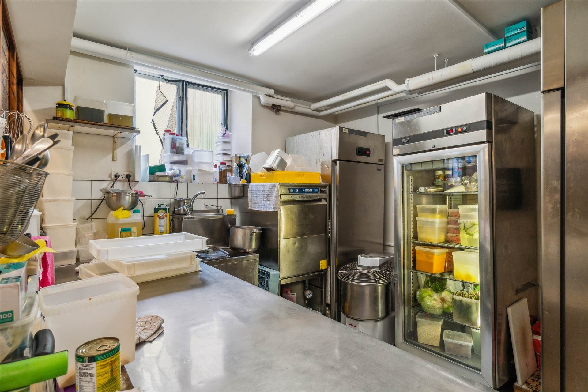 En køkkendel med flere apparater, blandt andet en komfur, en mikrobølgeovn og en køleskab, samt flere køkkenredskaber og