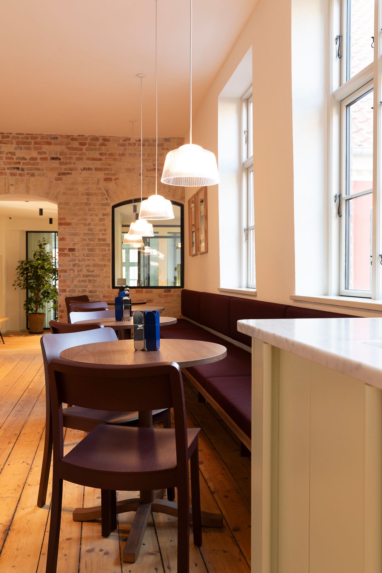 Værelse med en rund bord og stole, lysekroner og spejl i baggrunden og trægulve