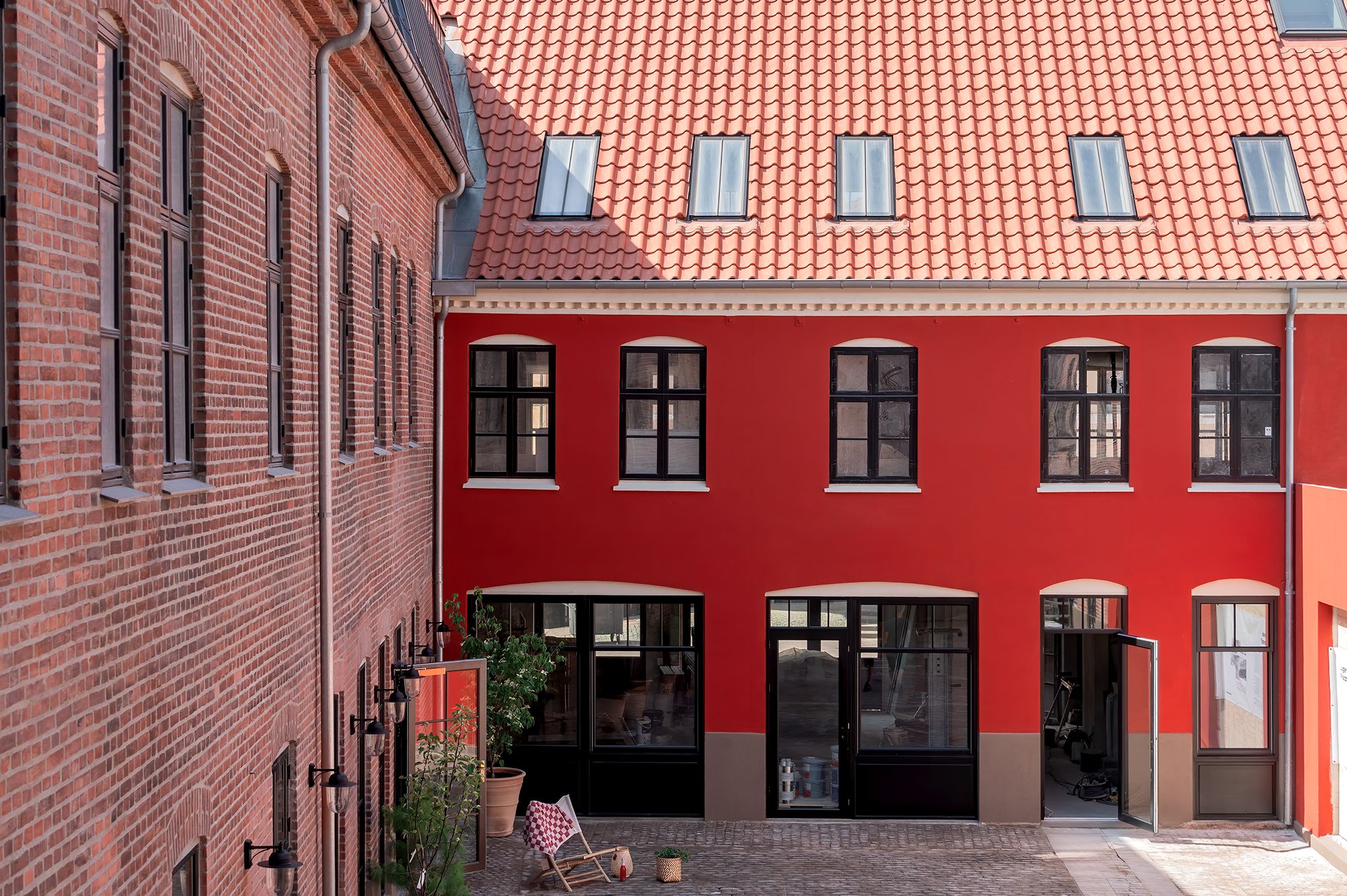 Kontor bygning med røde vægge og glasruder med møbler og plantager i forgrunden