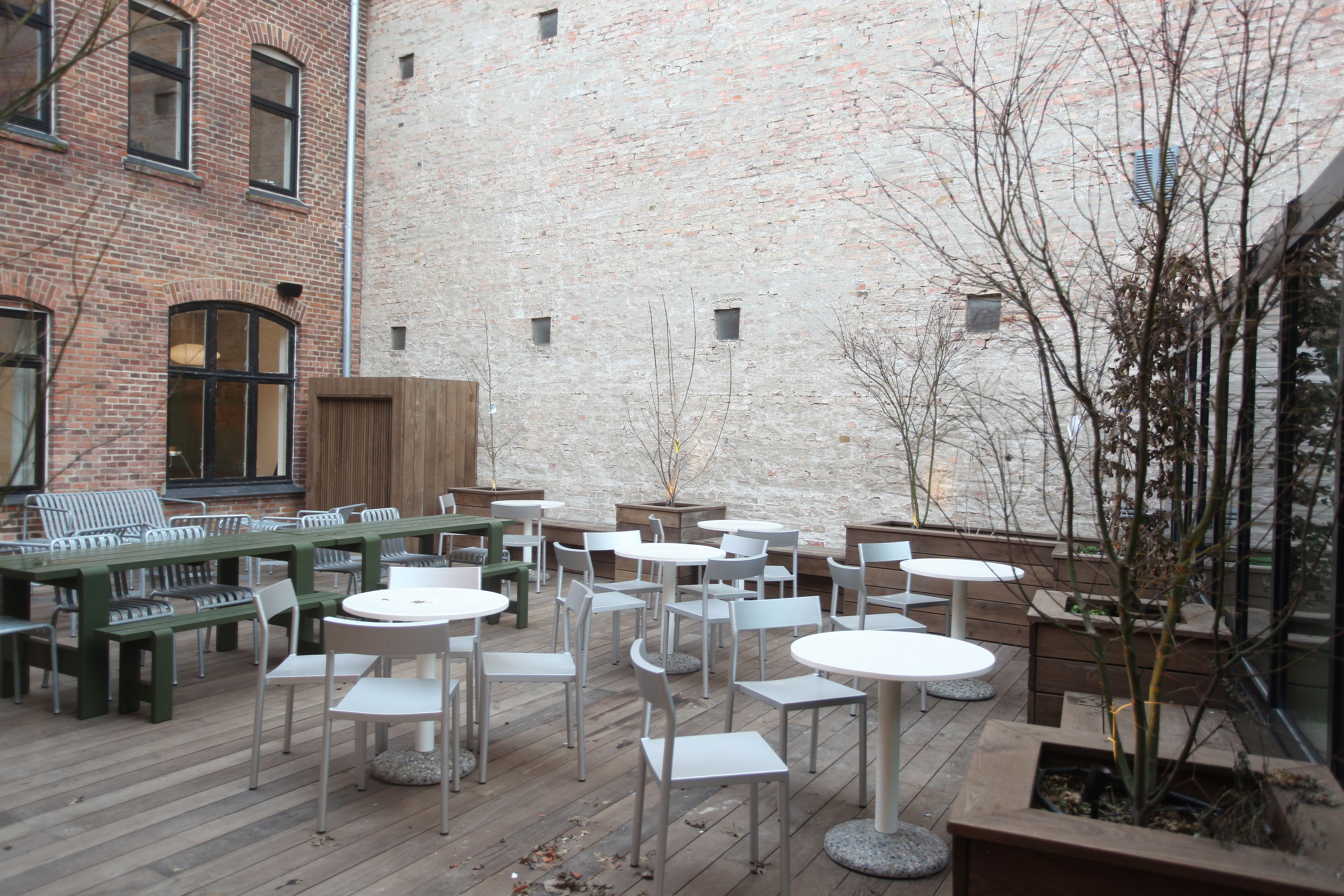 Et moderne og luksuriøst kontorområde med lyse trægulve og lyserøde murstensvægge. Der er flere hvide borde og stole samt et