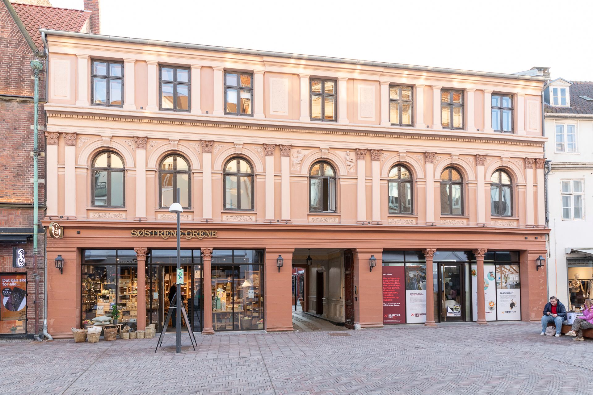 Foto af bygning med facade udsmykket med vindue og indgang til butikker og Nordstens Workspace på Hillerød Torv