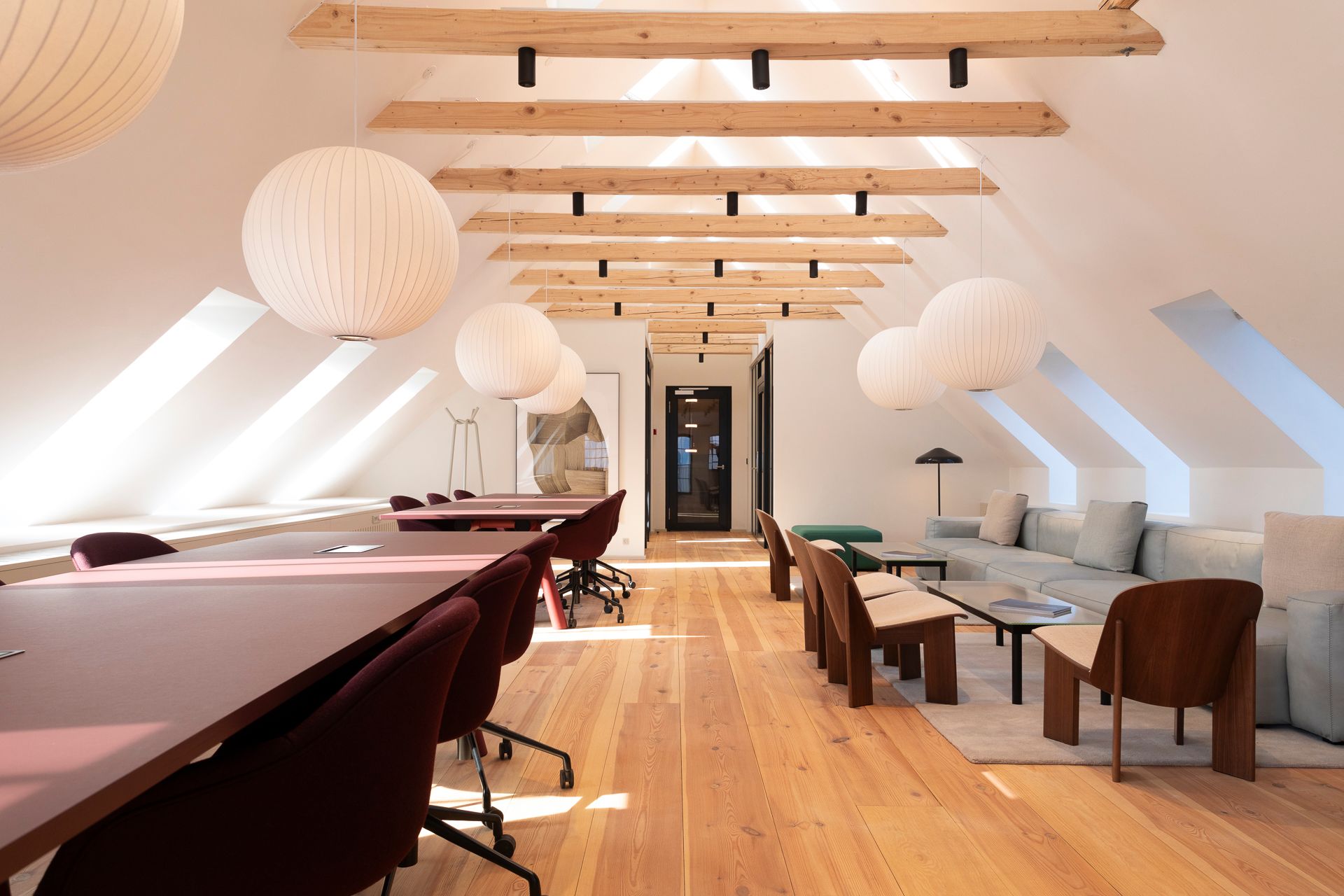 Lys, lyse loftsrum med lyse trælofter og hængende kugle-lamper, lysegule vægge og en række møbler