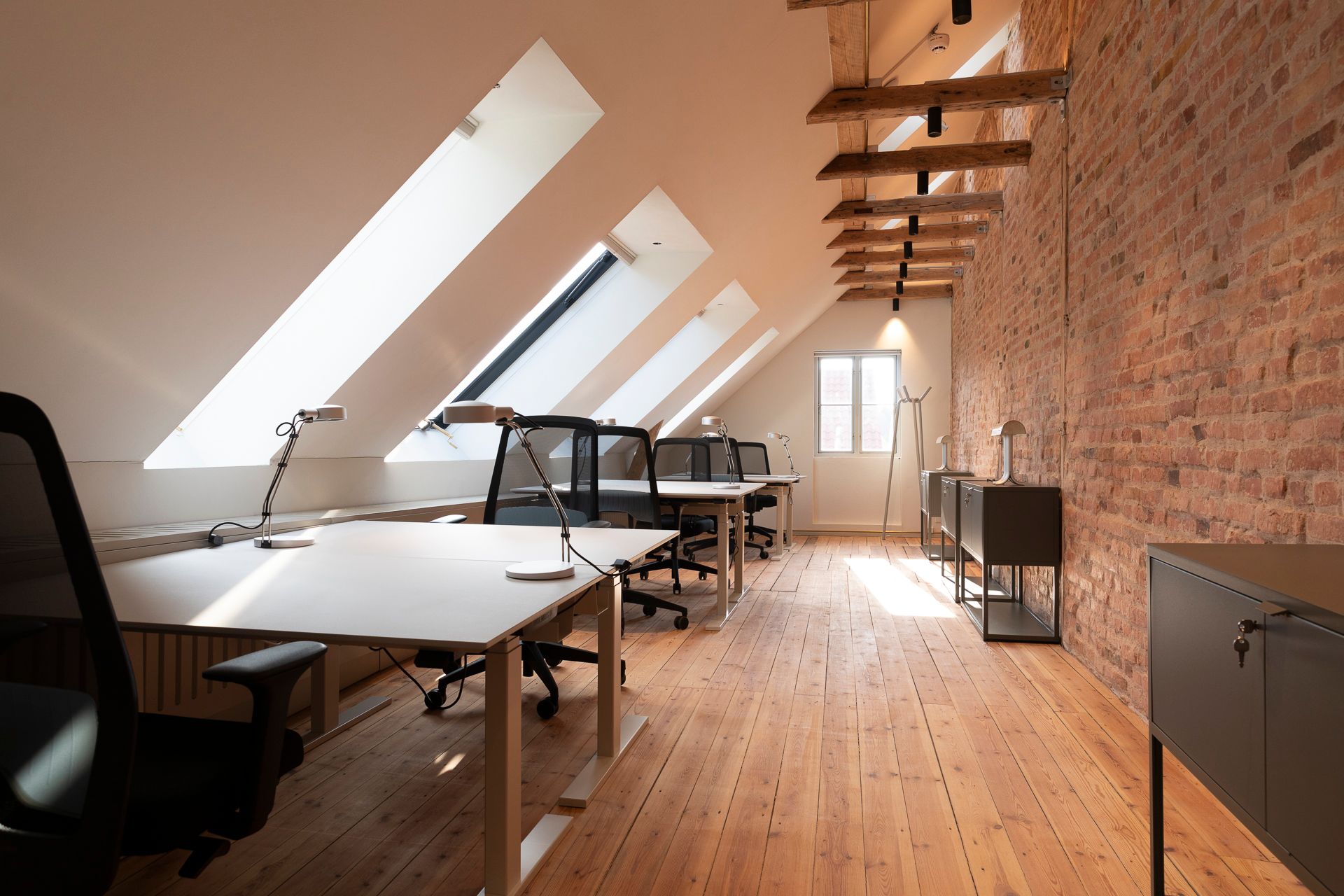 En moderne arbejdsplads med højloftede rum, lyse lofter, trægulve og møbler placeret i et nyt kontorområde i Hillerød