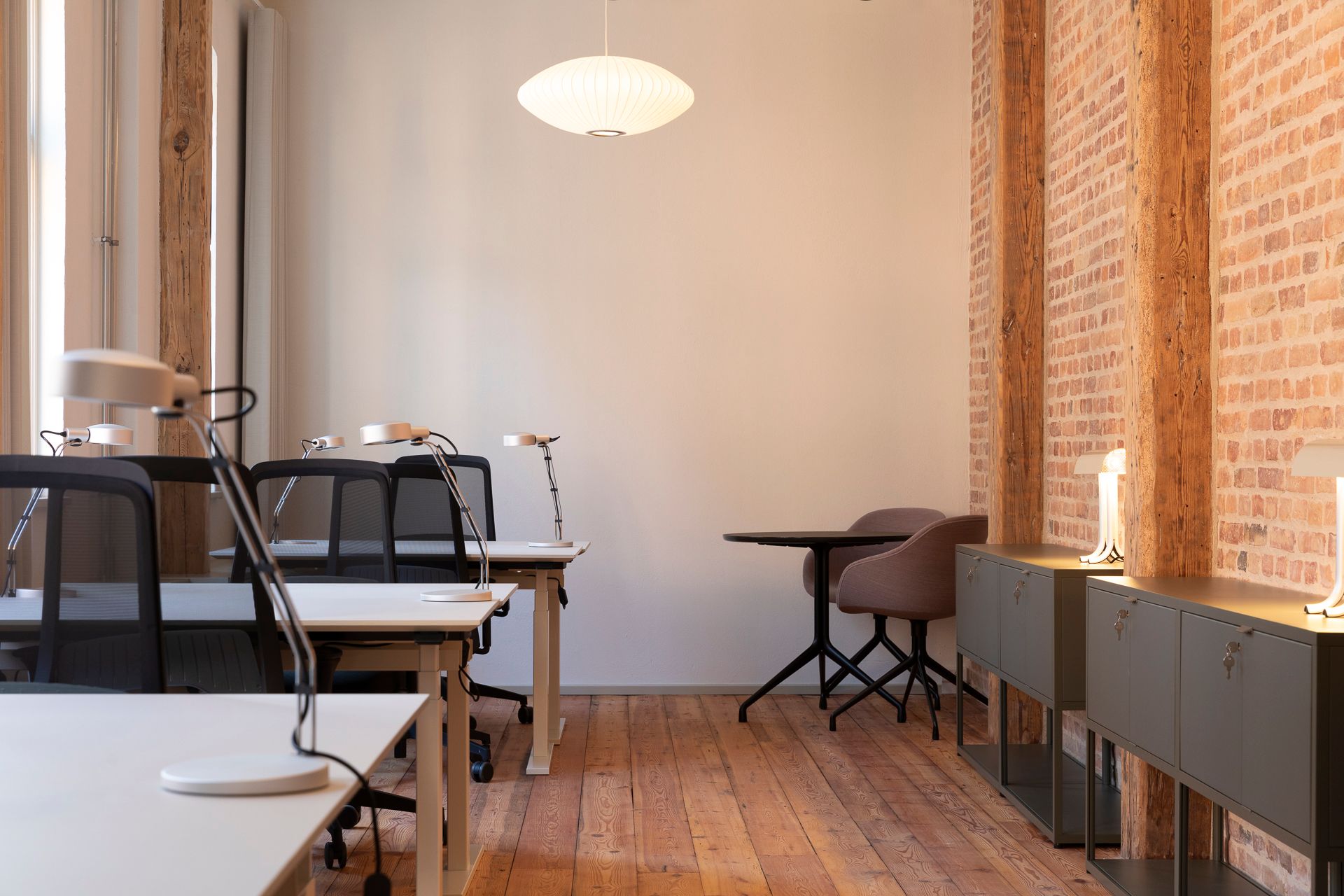 Kontor med lyse, lyse lamper, høje vinduer og lysegule vægge. Trægulve og stole med høje sæder og stolpebeklædning