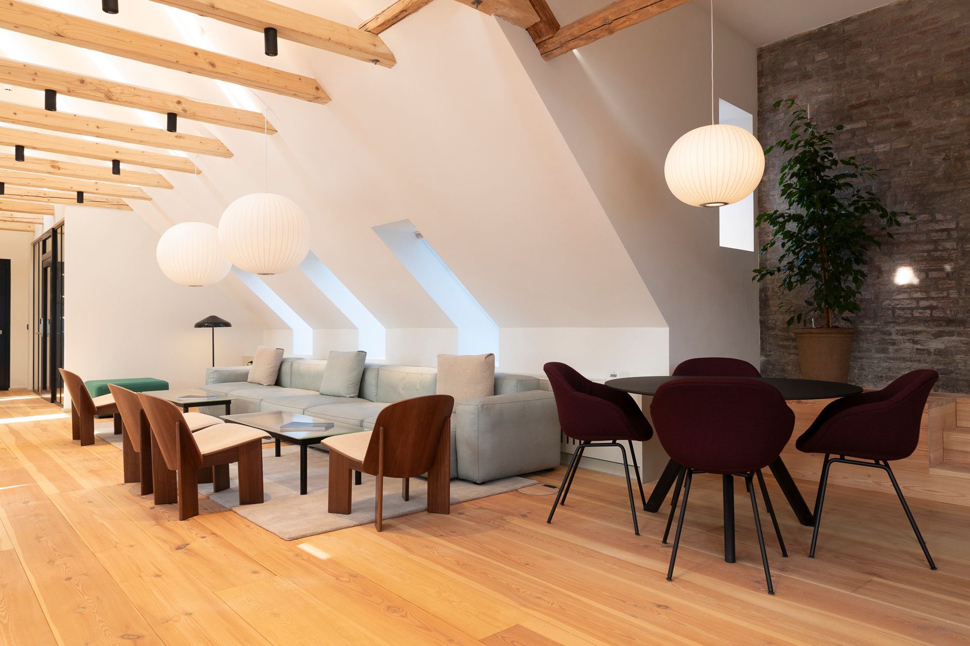 Elegant loft værelser med højloft og trægulv. Rundt bord med fire sæder og massivt træ sofa med puter. Loftet er dekoreret