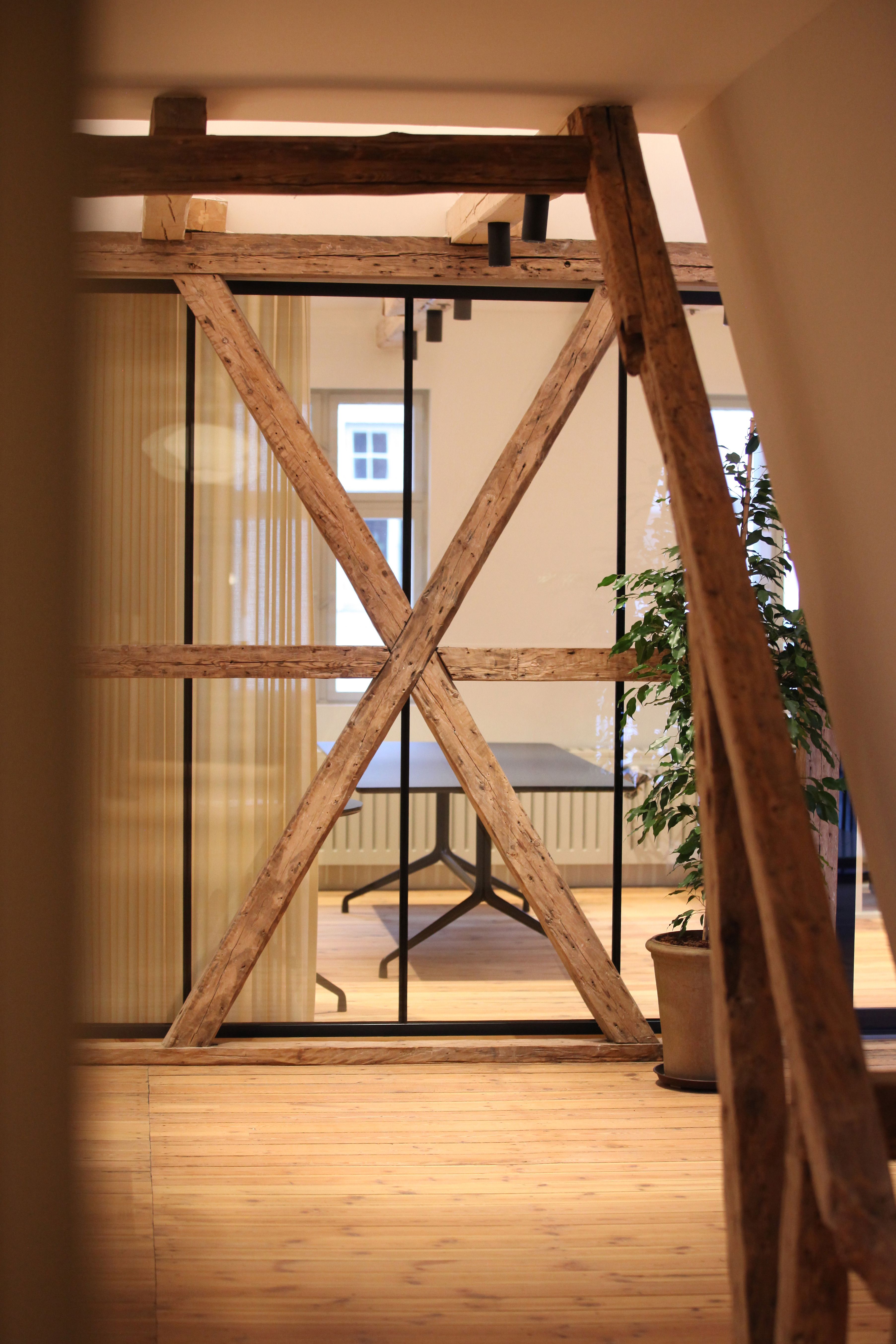 Indvendig i et kontorlokal med træbjælker, en bord og en plante i en potte