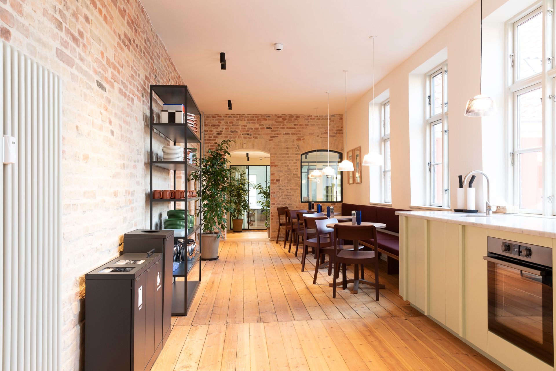 Moderne og rummelig kontor med trægulve, hvide vægge og røde mursten. Loftsvinduer, slanke lysekroner og en komfortabel