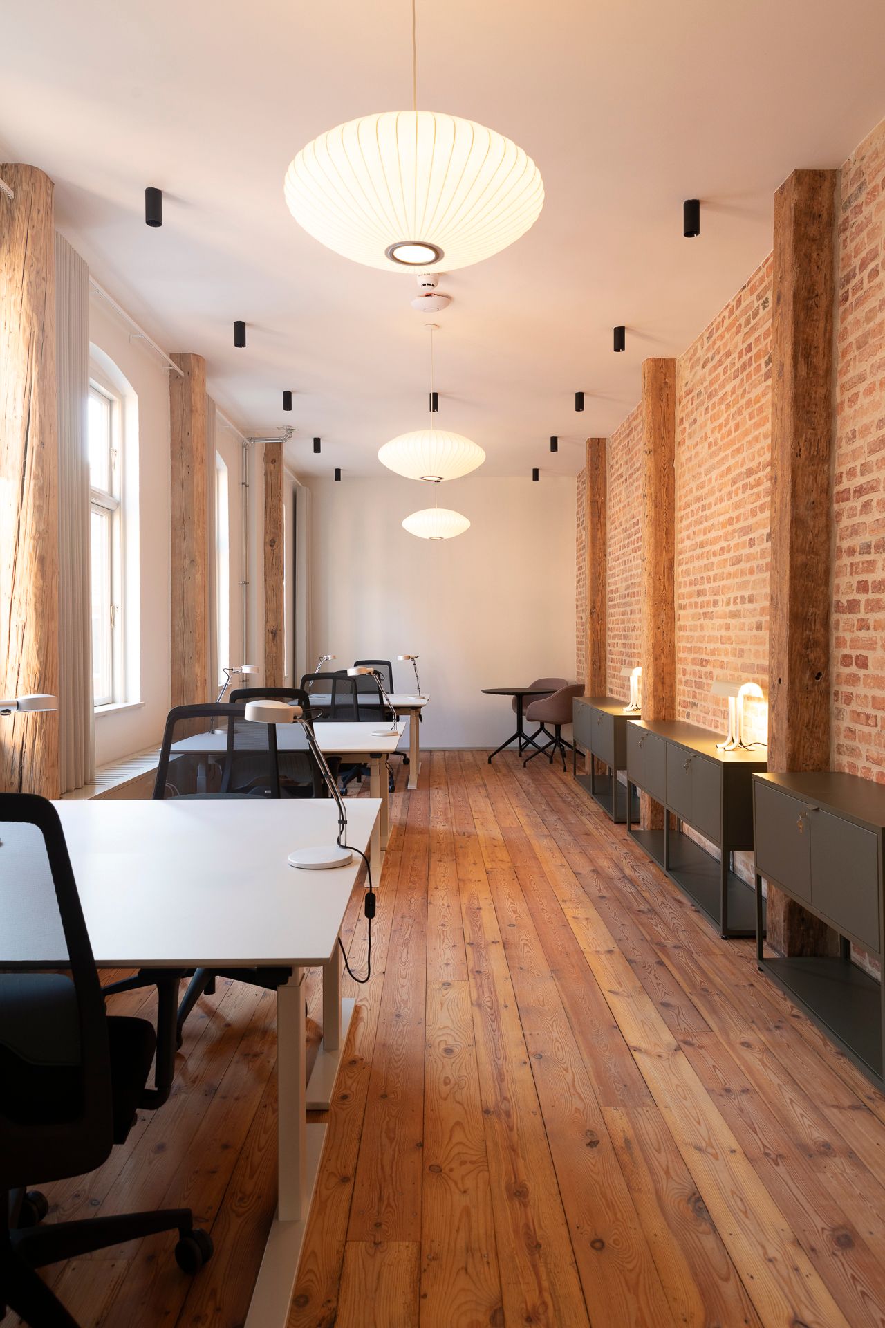 Et moderne kontor med højt til loftet og lyse loftslamper i loftet. Der er stolpe til gulvet og store vinduer med