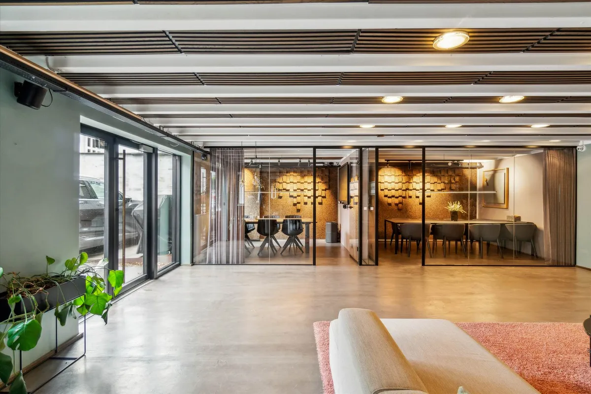 Moderne kontor med beige sofa og lysegrå gulv samt lysekroner og slanke glasvinduer i en stilfuld lysegrå indretning