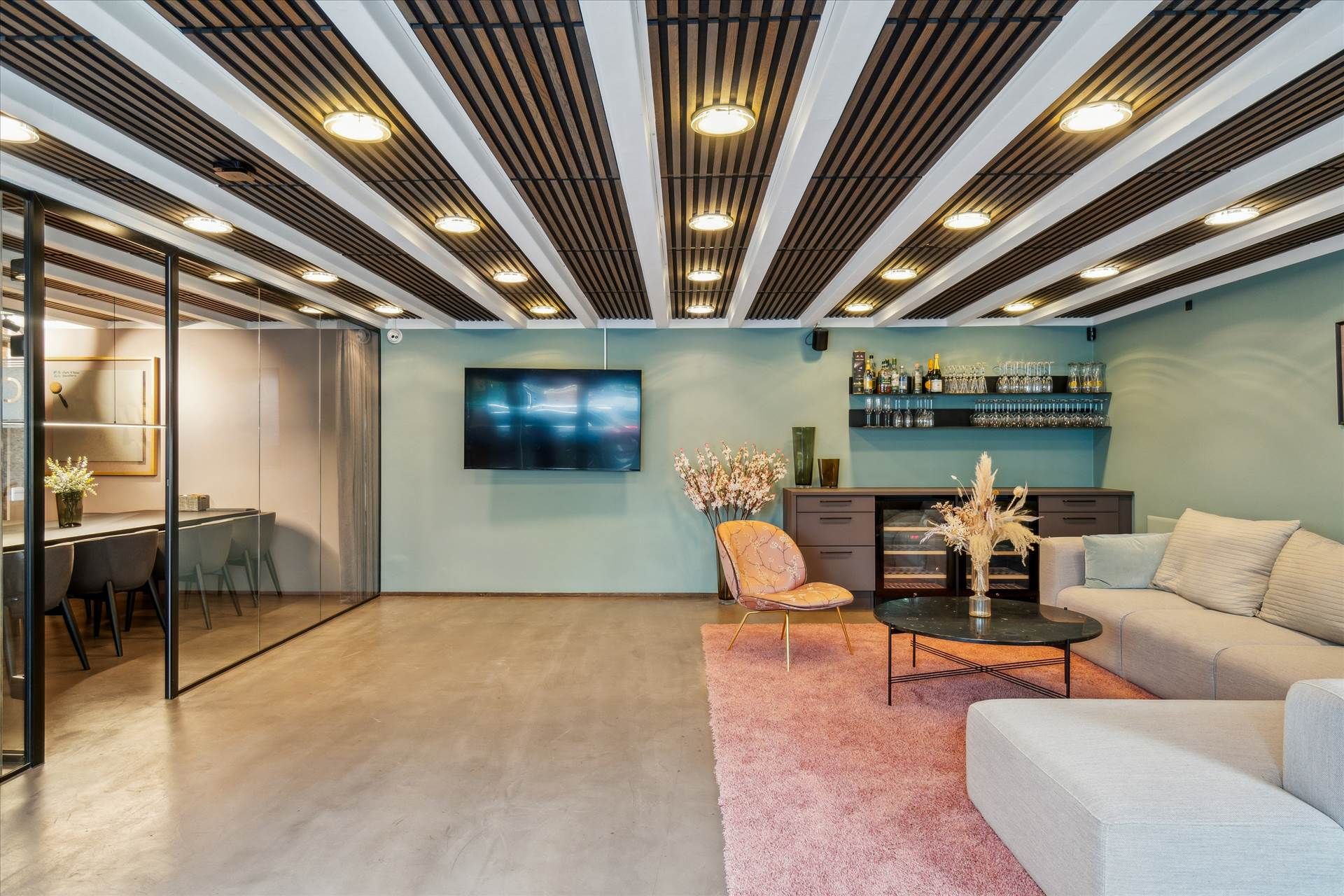 Stilfuldt kontor med højloft, gulv i beton og højt gulv. Her er sofaer, stole, skrivebord og tv-skærm