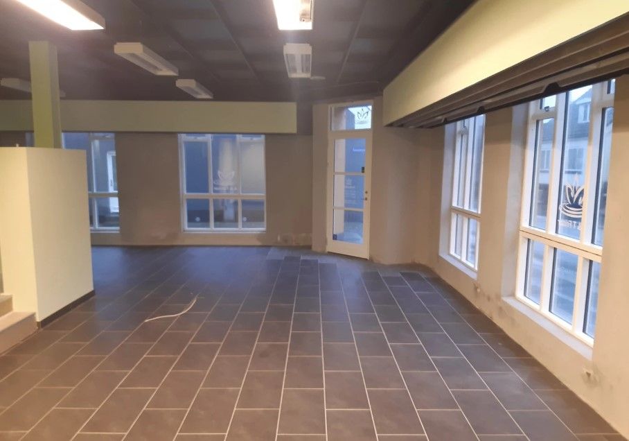 En tom kontorlokal med trægulve, store vinduer og lysekroner i loftet - et rum til leje i Glamsbjerg