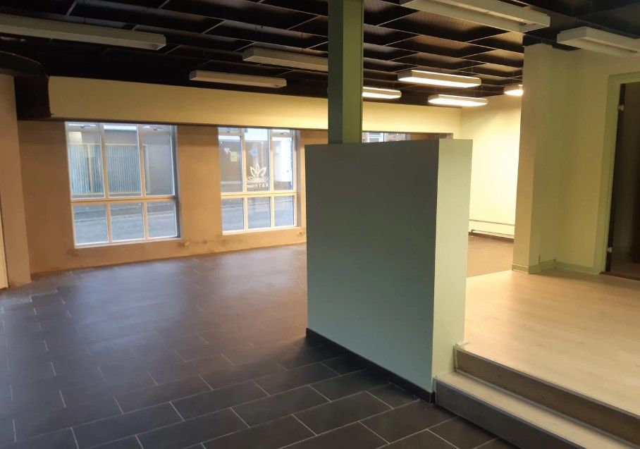 En stor, tom, lys hall med en sort gulv og hvide vægge og vinduer med store, hvide gardiner