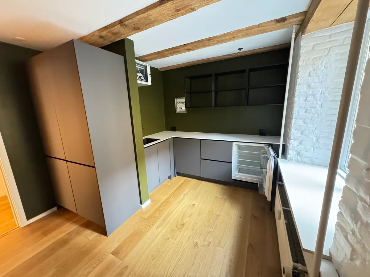 Foto af en moderne køkken med lyse trægulve, høje lofter og hvide vægge samt en stor køleskab og et komfur