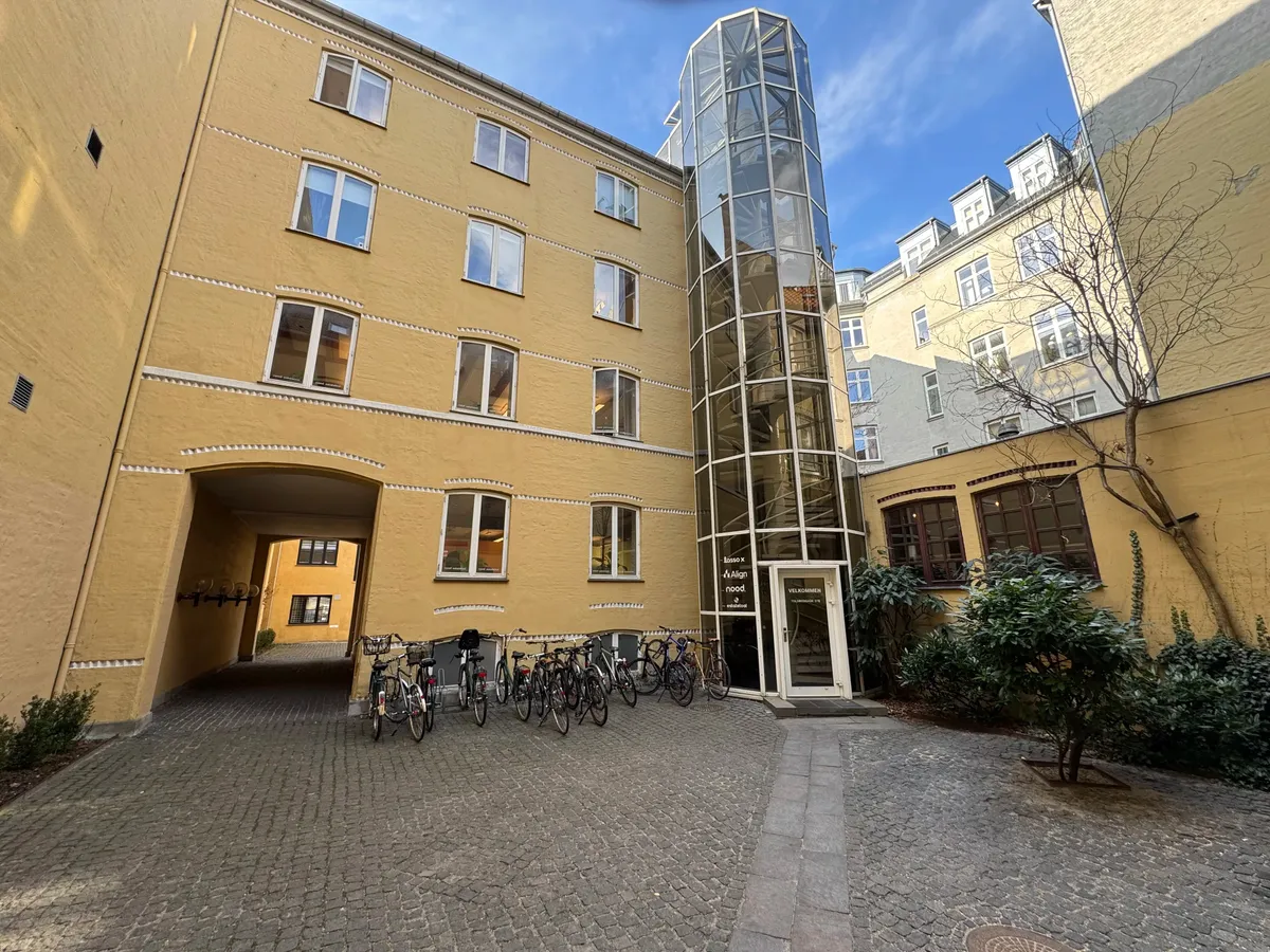 Lejlighed med gårdhave, vindruesving, glastrapper og udsigt til skyerne i Frederiksstaden med smukke lysegul facade