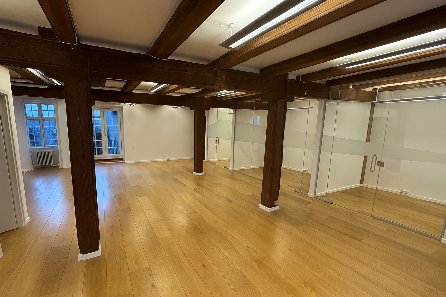 Kontorlokaler med træloft og glasvægge samt hårdt trægulv og lyse glasruder