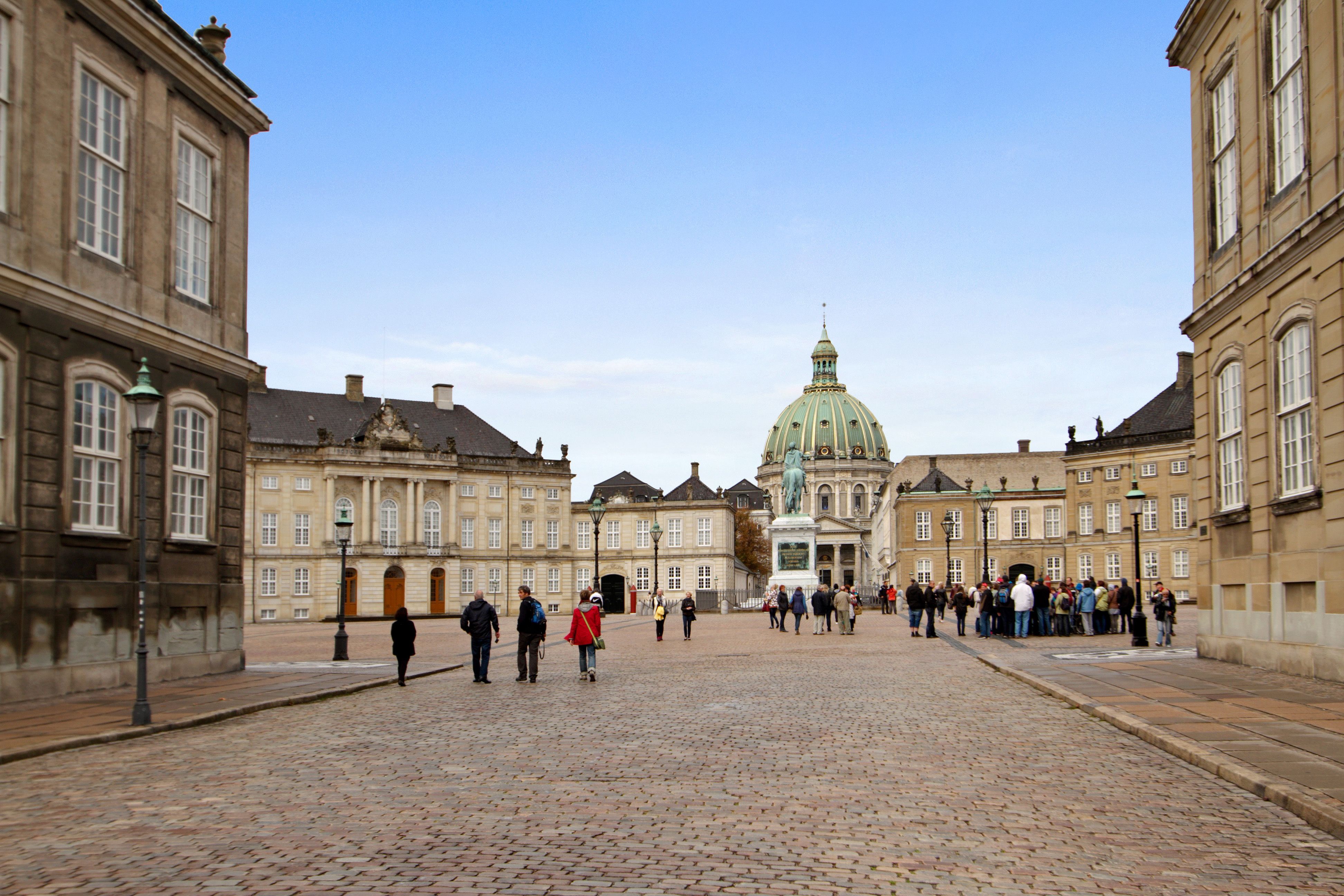 Folk går i Frederiksstaden med Charlottenborg og Amalienborg i baggrunden, og der er en statue foran Charlottenborg