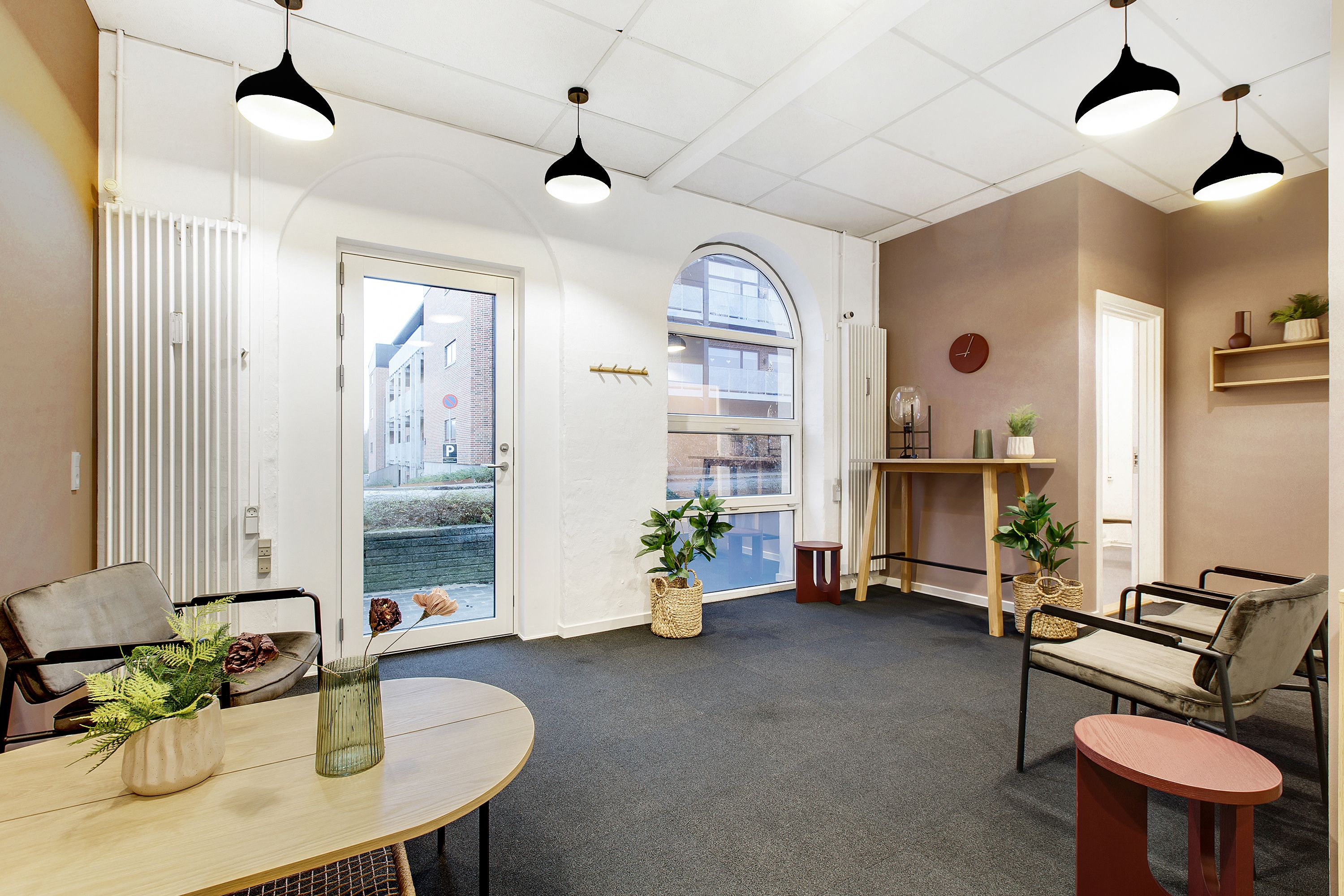 Klinkfællesskab i Kolding med plantepotter, lysekroner og en hvid dør til et værelse med et smil.