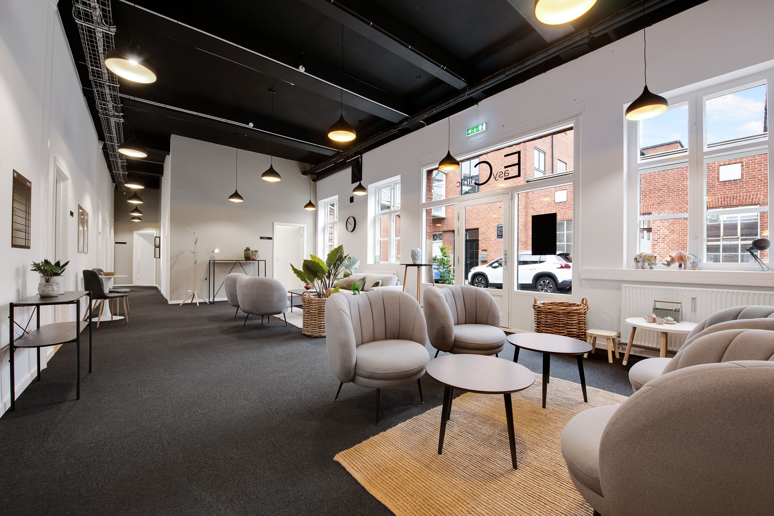 I et moderne og åbent lokale med hvide vægge og møbler i lysgrå farve. Væggen er dekoreret med kunstværker og der er