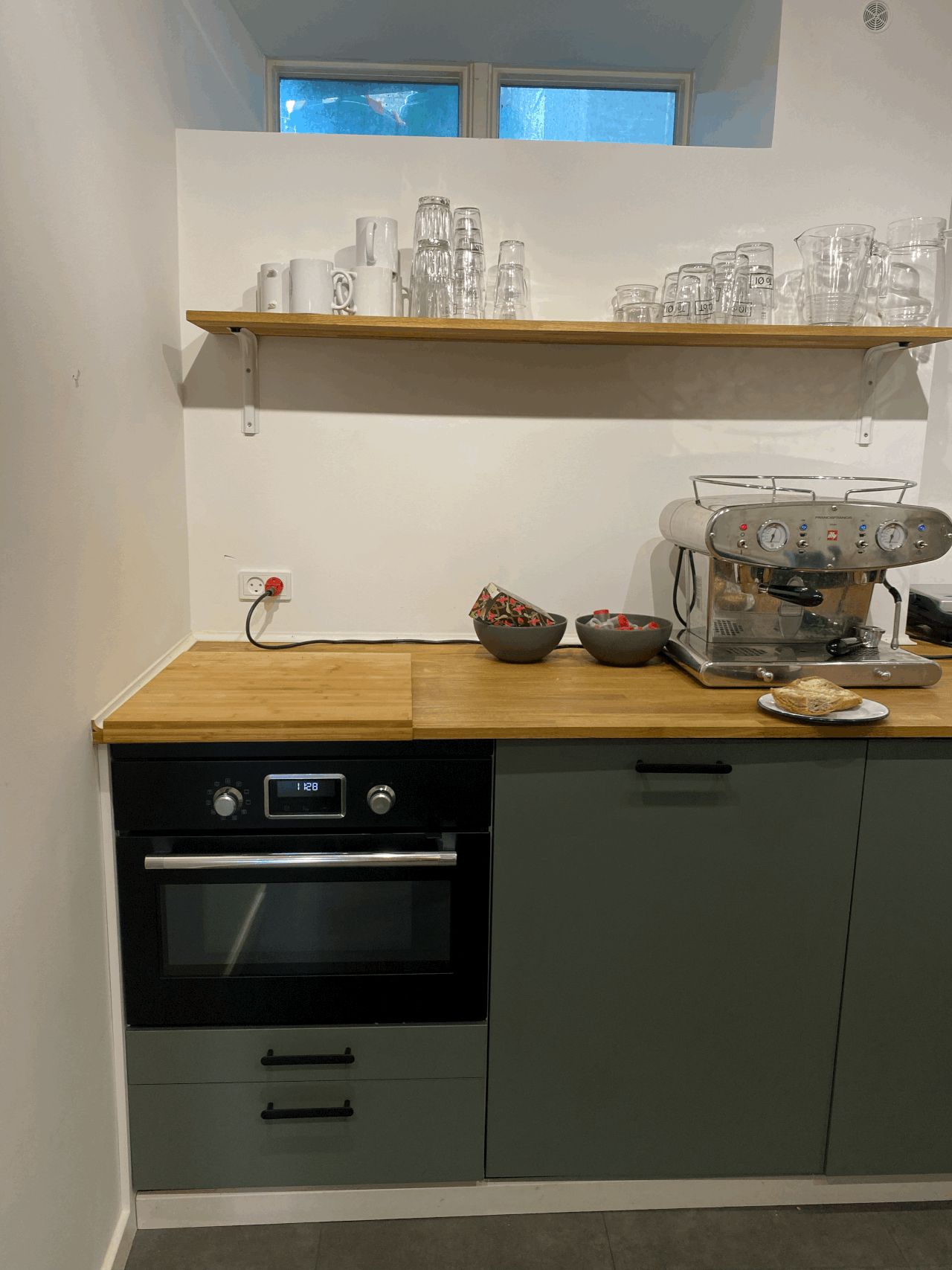 Kontorlokale med køkken med keramik, glas og kaffemaskine og en ovn med digital display og to skuffer