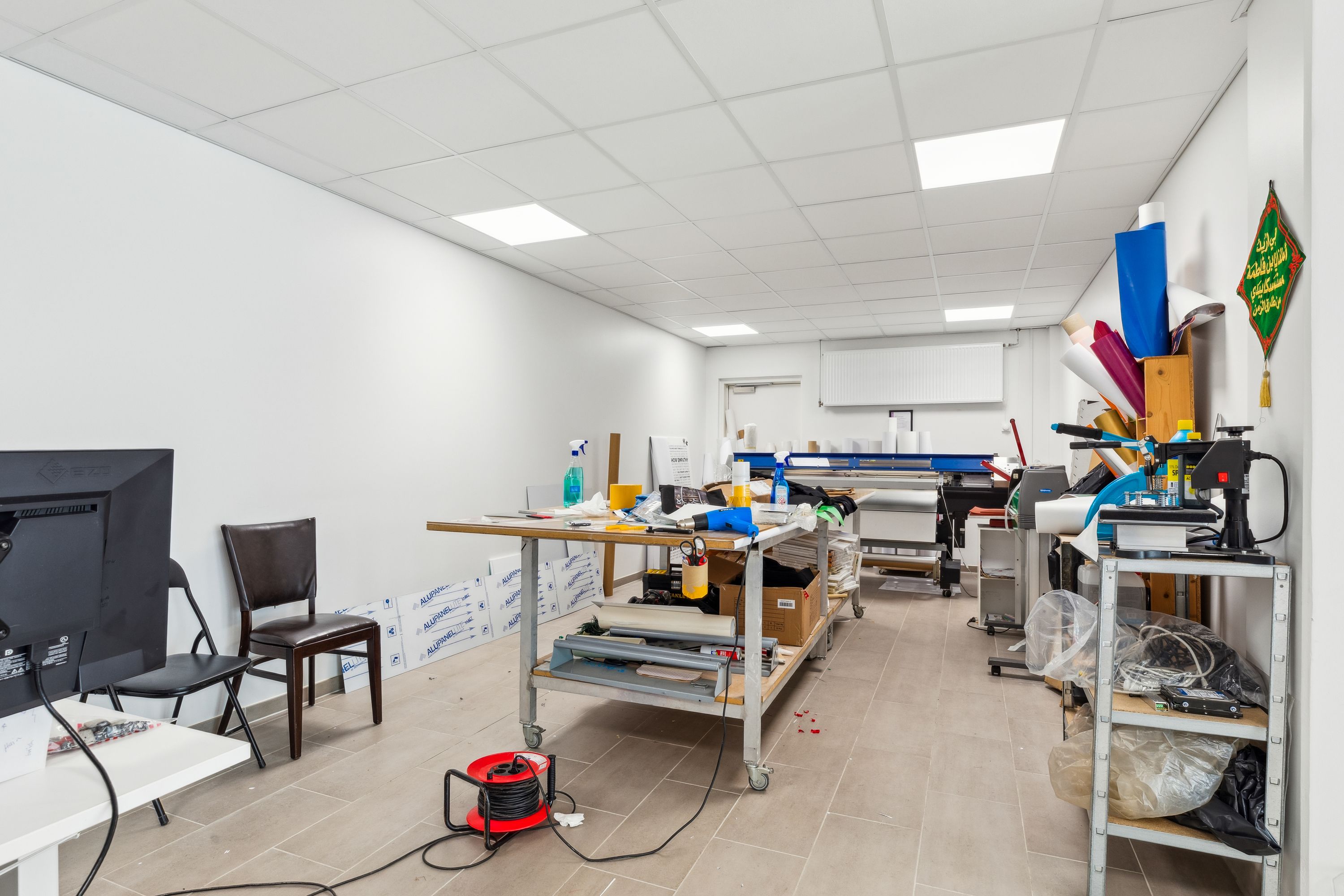 Inde i lokalet er der flere borde med diverse udstyr, herunder en printer og en svejsemaskine. Der er også en tv-skærm, to