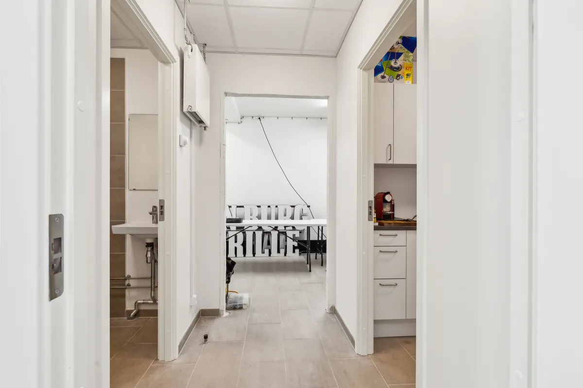 Lejlighed med to separate indgange og lyse gulve, hvor en indgang fører til et køkken med lyseskabe og et badeværelse med