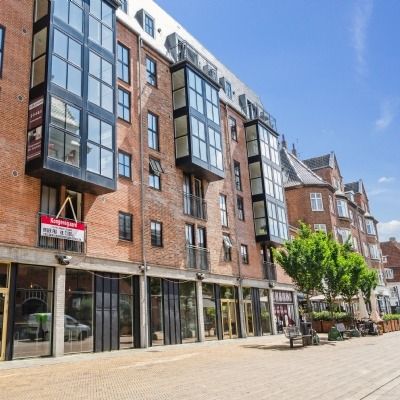 Bryggergården er en ny lejemål i Odense City. Bygningen med store glasruder er nyrenoveret. På gaden er der bænke og træer.