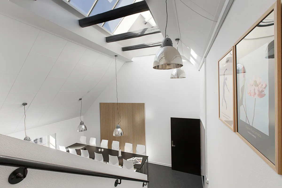 Kontorlokaler med møbler og loftsvinduer samt lysekroner og vægbilleder