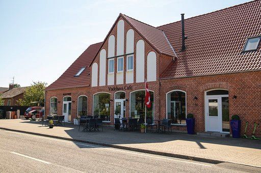 Billede af en ny cafe med bord og stole udenfor og en flagstav med dansk flag