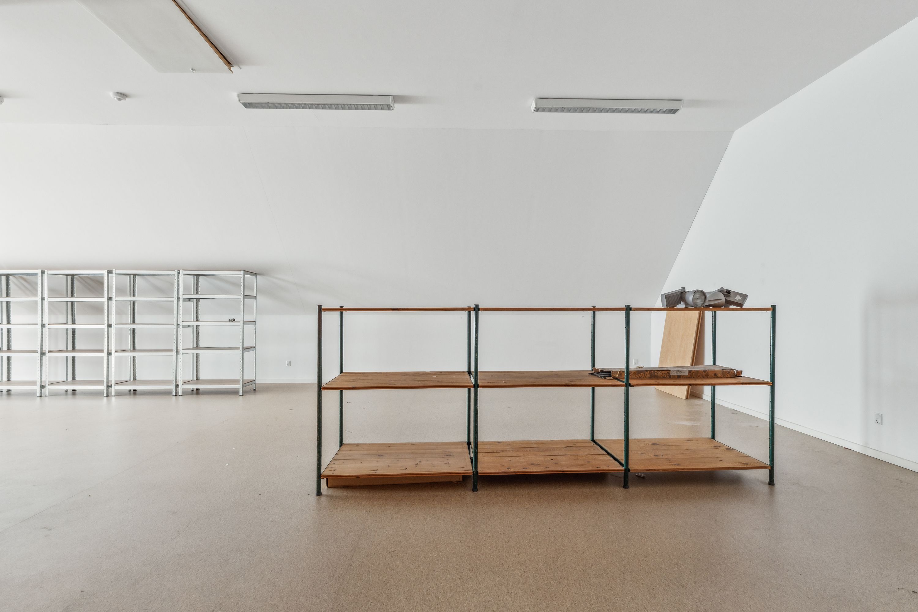 En tom kontorbygning med to rækker af stelreoler og tre stelreoler med træhylder og en trækasse placeret på den ene side