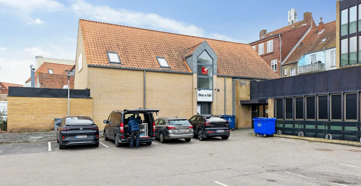 Fire biler parkeret foran Bog & Idé bygning, man henter hundekasse op fra en kørevogn