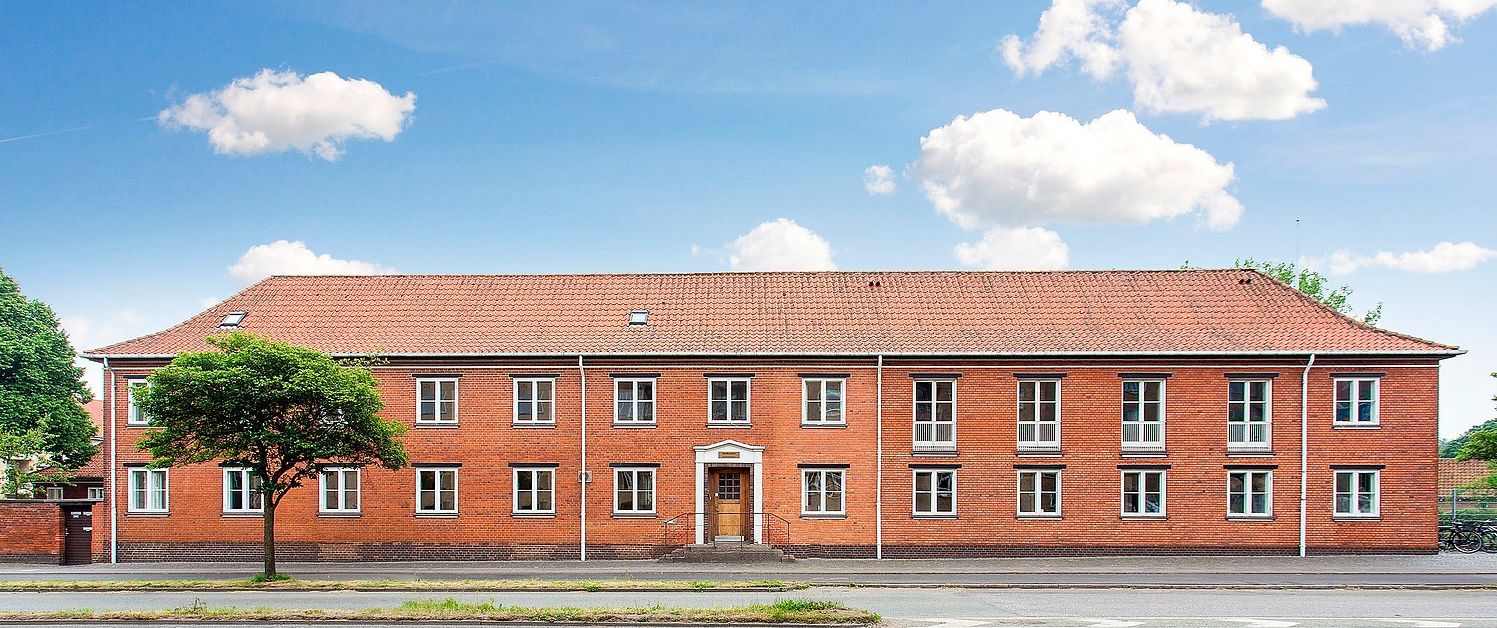 En stor rødmaursten bygning med mange vinduer og en stor port i midten