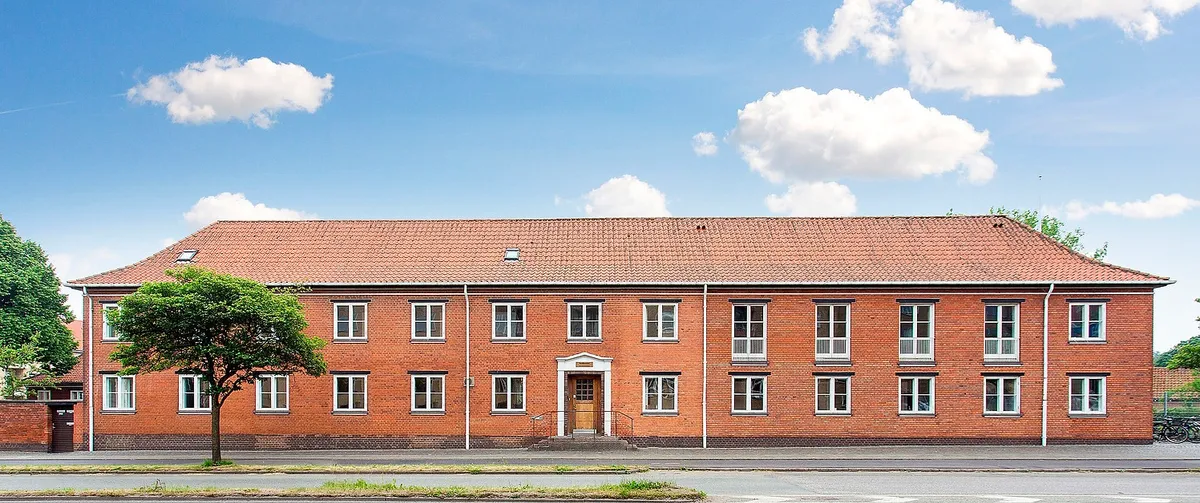 En stor rødmaursten bygning med mange vinduer og en stor port i midten