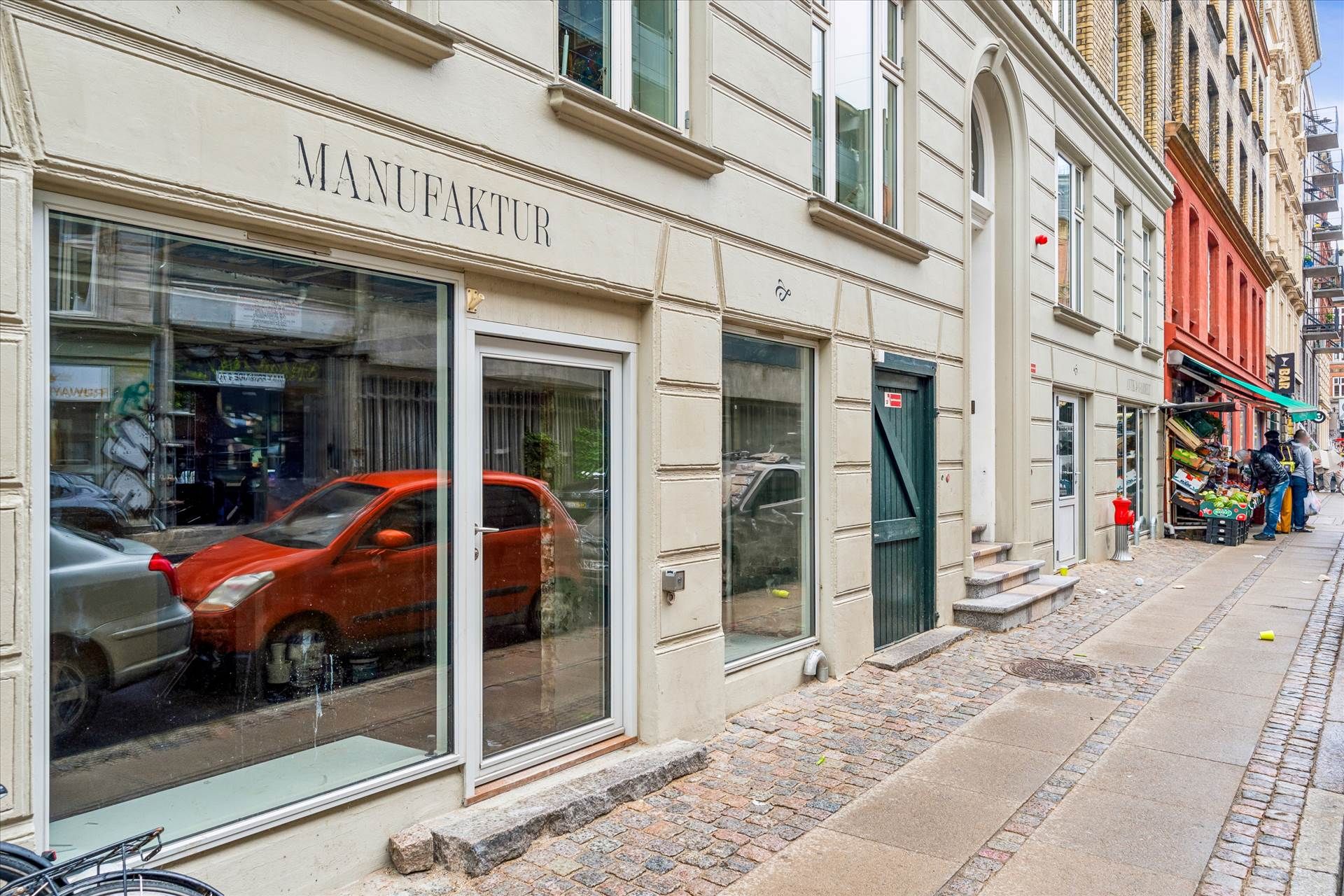Erhvervslejemål på Griffenfeldsgade med butik og kælder samt parkerede biler og grøntmarked