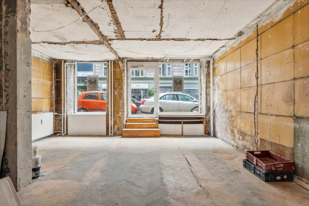 Lejlighed med nyt loft og renoverede vinduer, to biler parkeret udenfor og to rødbrune kassevognskranke i lokalet