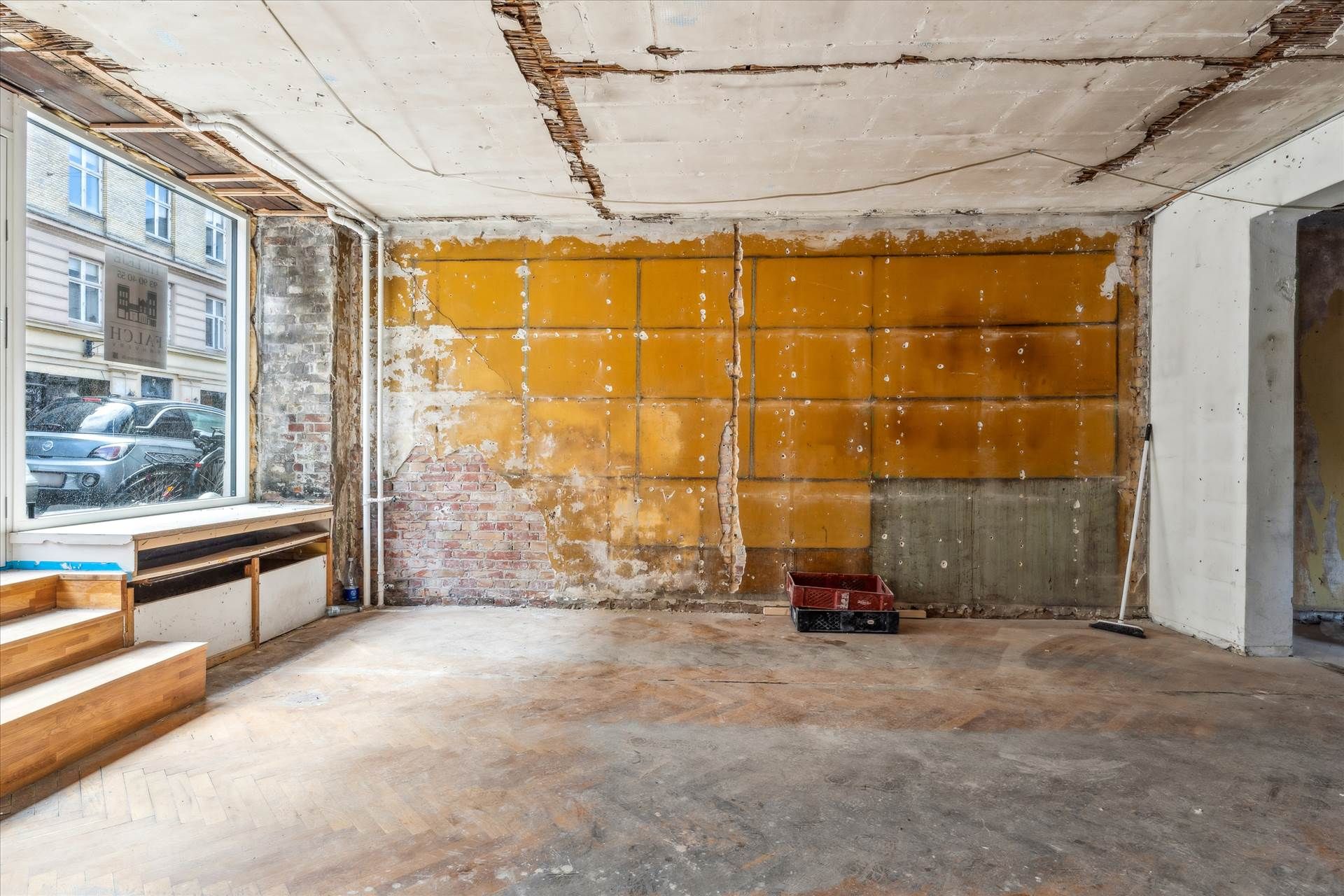 Rå og renoveringsvenlig lejemål med udsigt til gårdhave, gammelt vægmaleri, gulve i træ og en stor vinduesfordybelse med
