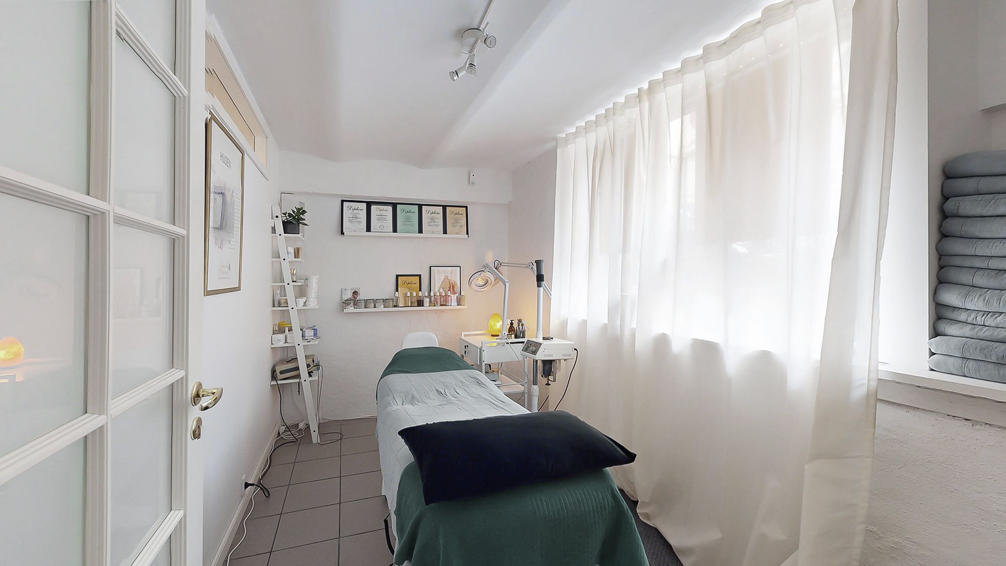 Lejlighed med en massageseng, hvidt linned og en hvid kurtis. Der er et hvidt vinduesgardin, en hvid loftslampe og en hvid