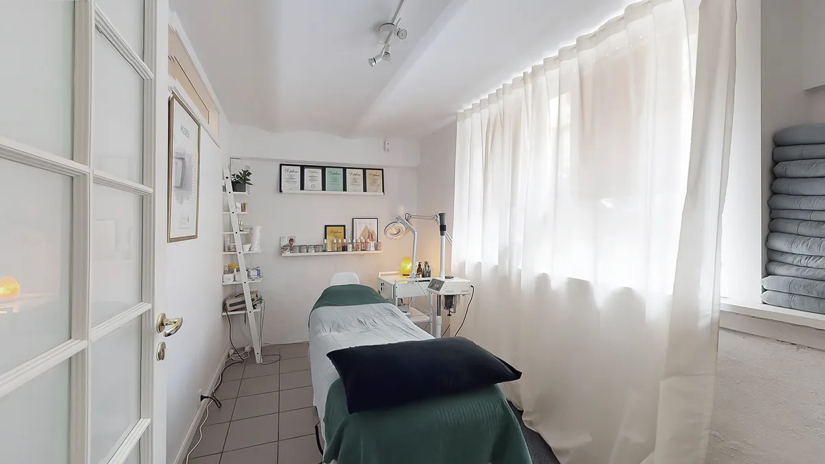 Lejlighed med en massageseng, hvidt linned og en hvid kurtis. Der er et hvidt vinduesgardin, en hvid loftslampe og en hvid