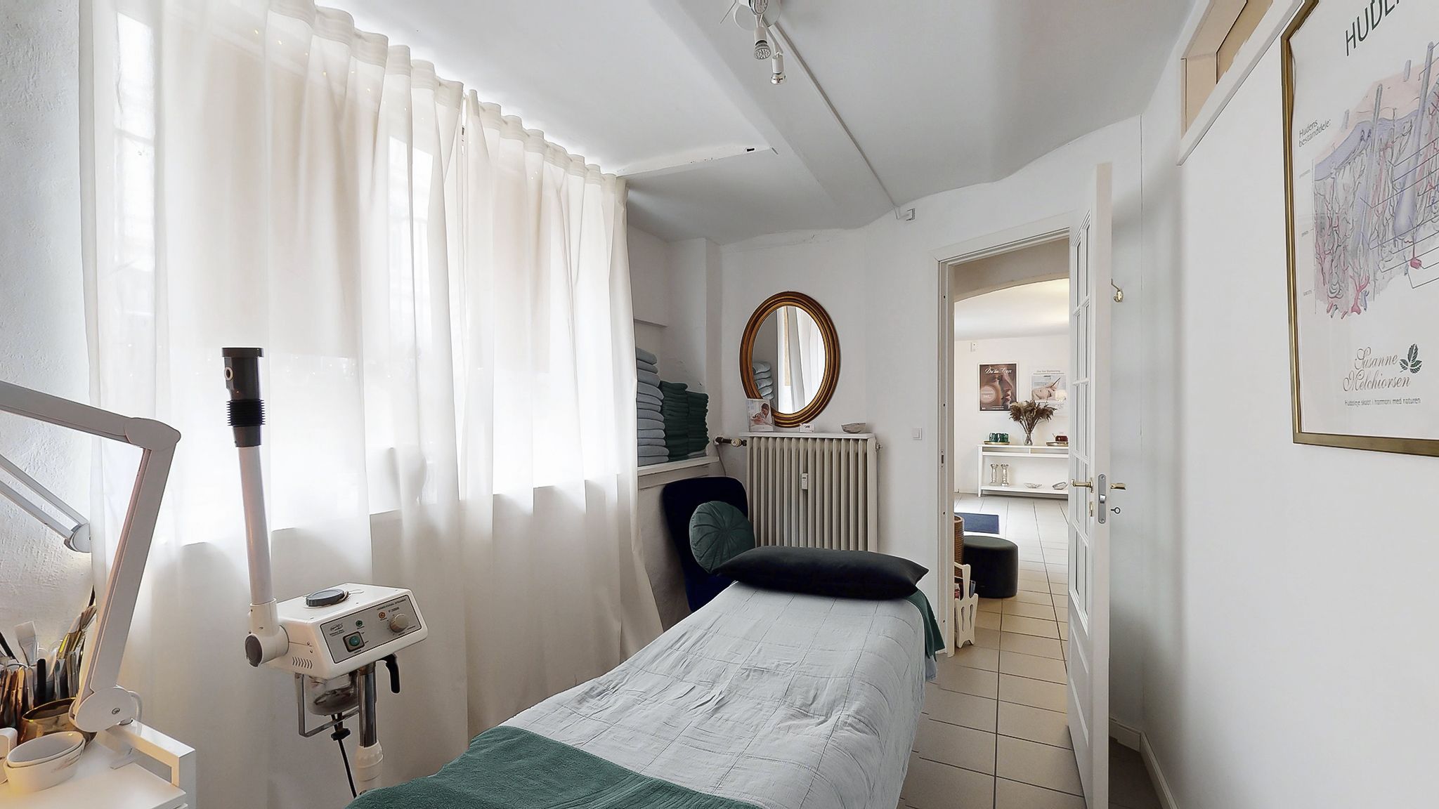 Et rum med et hvidt sengetøj, en komfortabel seng og et lille skrivebord med et hængende apparat