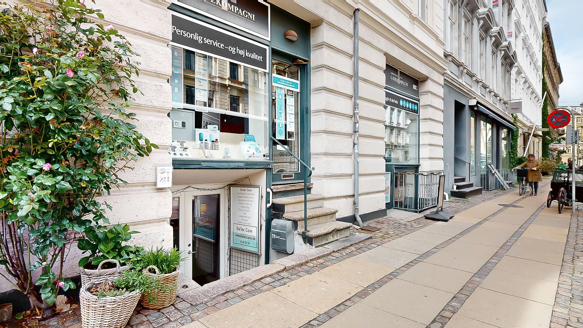 Butik med skrifterne Personlig service og høj kvalitet og Du Lac Care på søjle. Stiger og trapper fører op til butikken. En