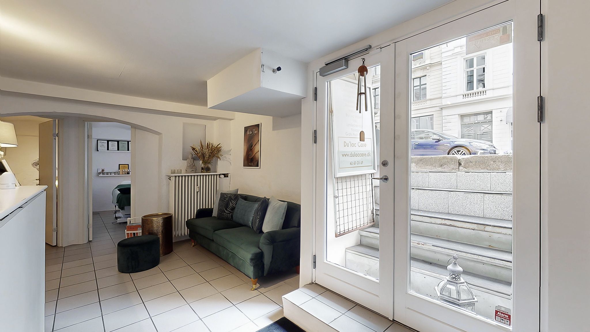 Velkommen til et elegant og komfortabelt værelse med en grøn sofa, hvidt gulv og en vidunderlig udsigt til en bilparkering