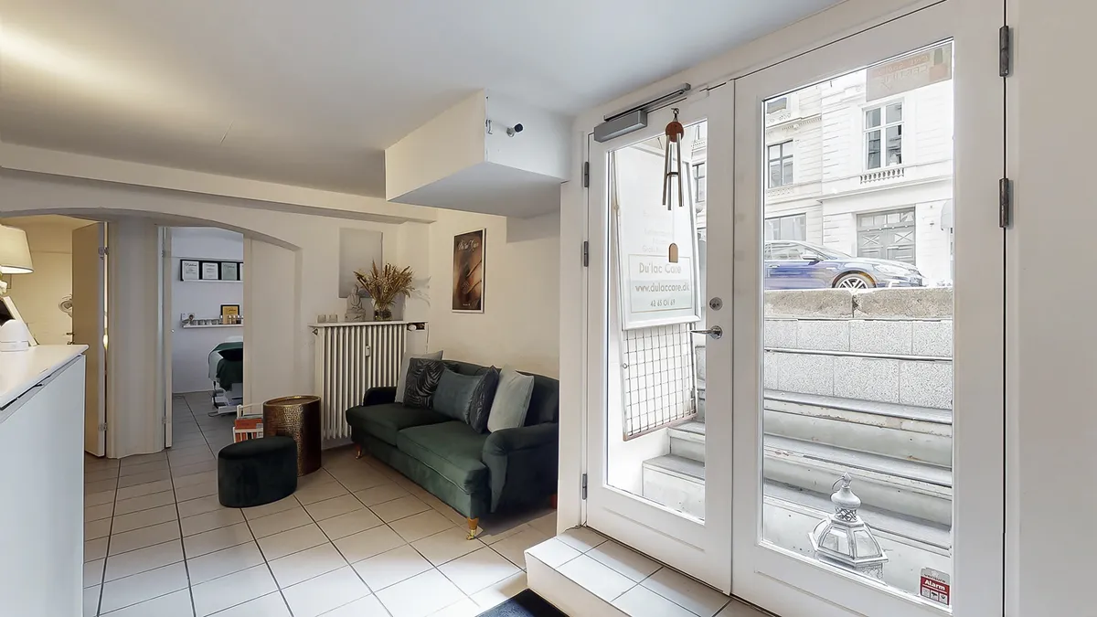 Velkommen til et elegant og komfortabelt værelse med en grøn sofa, hvidt gulv og en vidunderlig udsigt til en bilparkering