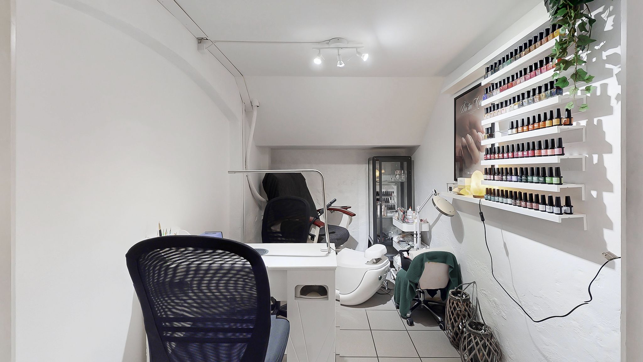 Et luksuriøst manikørsalon med hvid interiør og masser af opbevaringsrum til neglelak. Der er en barberstol og en masse